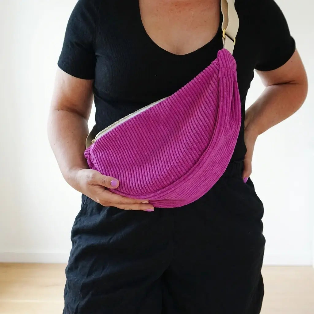 Sac banane fuchsia en velours côtelé porté en bandoulière, boucle dorée et sangle beige