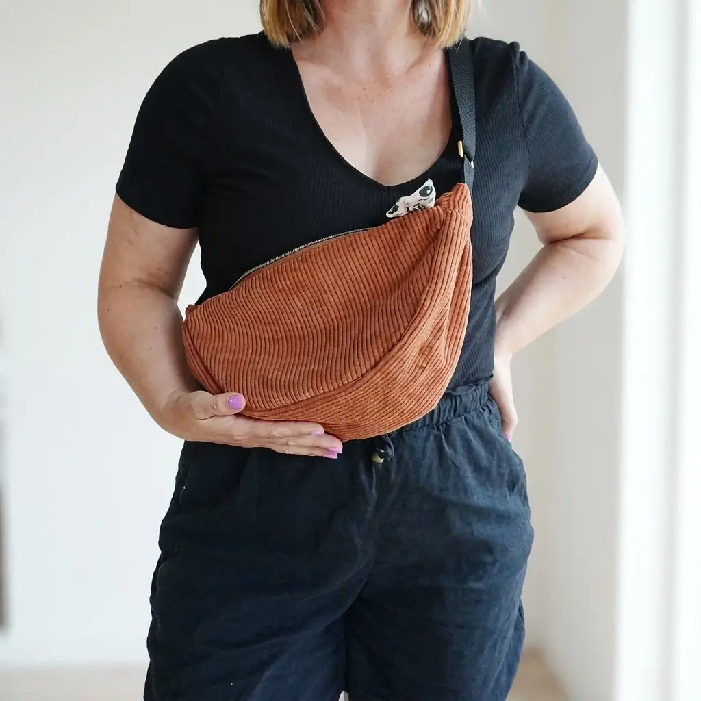 Sac banane marron en velours côtelé porté en travers avec une sangle noire réglable