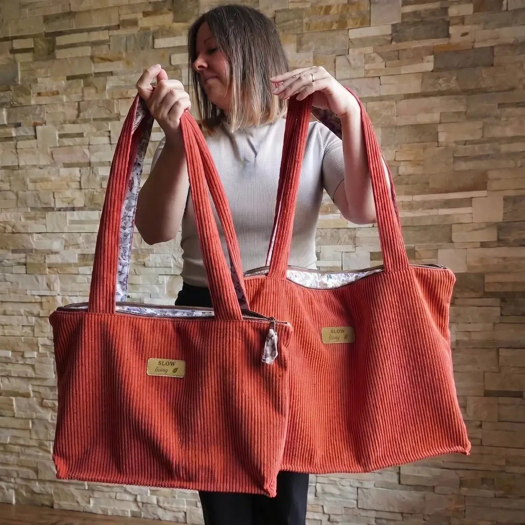 Comparaison de deux sacs cabas terracotta en velours côtelé, format classique et format XL tenus à la main