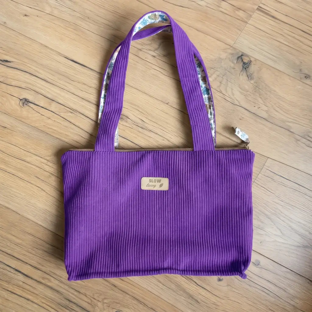 Sac cabas violet en velours côtelé vu du dessus, anses à doublure fleurie et zip beige