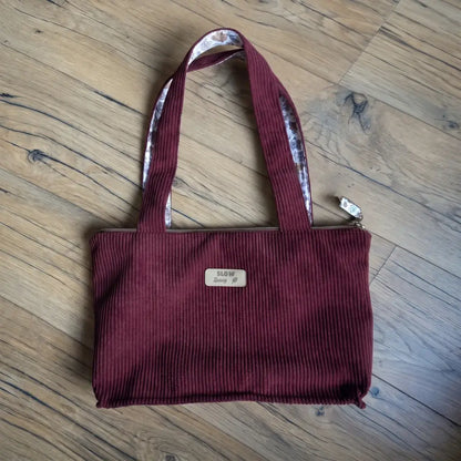 Sac cabas prune en velours côtelé vu du dessus, doublure fleurie visible sur les anses