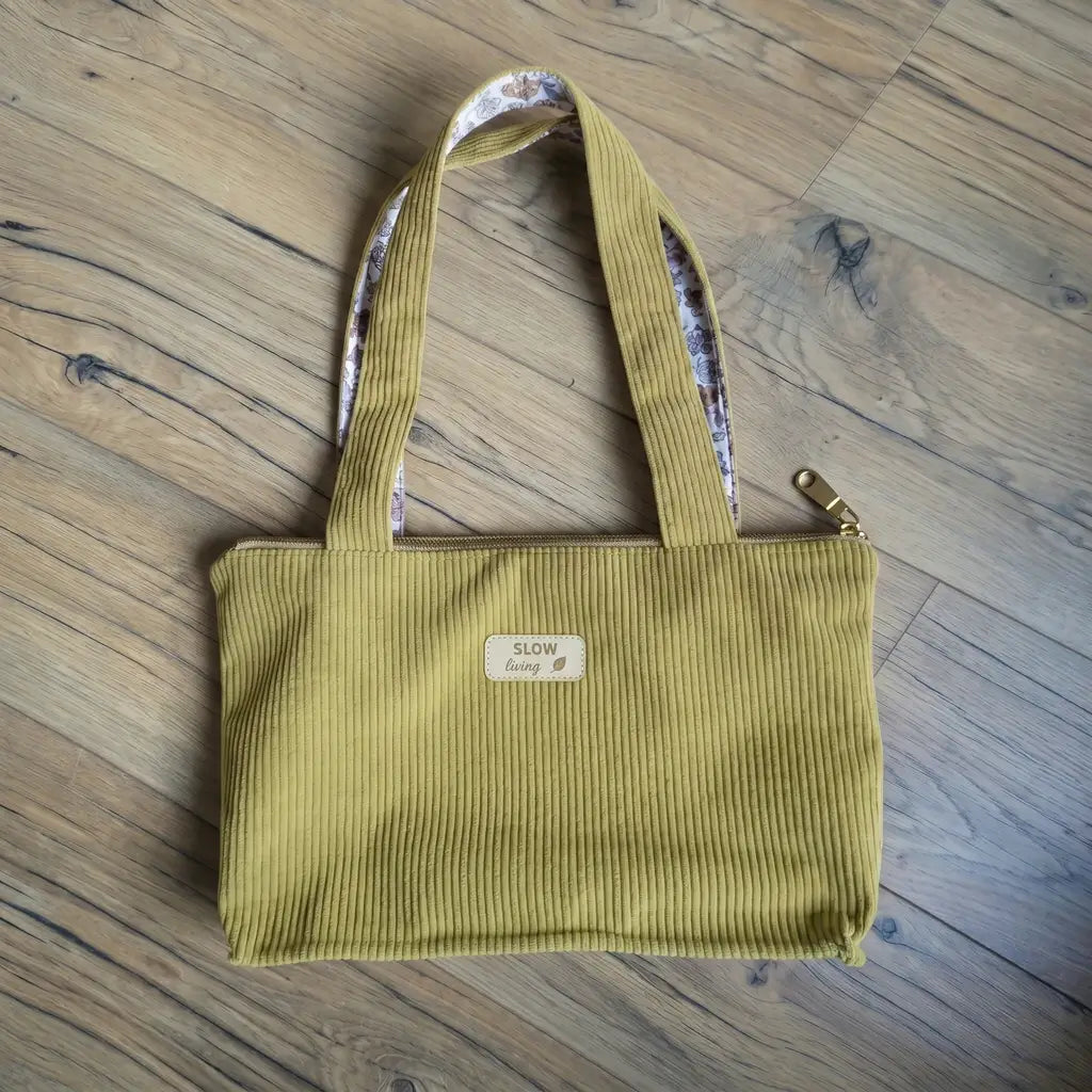 Sac cabas vert anis en velours côtelé posé à plat, zip doré et anses à doublure fleurie