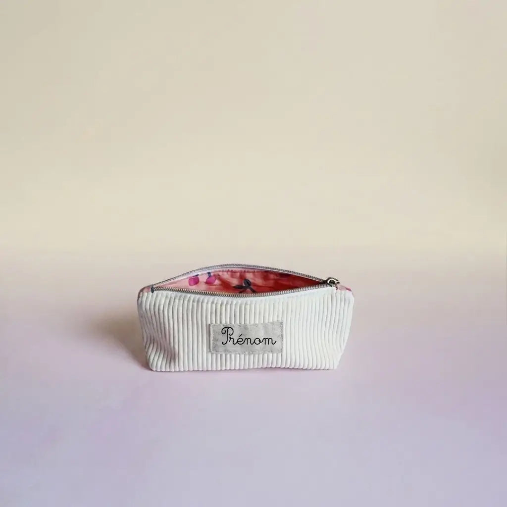 Trousse d'école blanc cassé en velours côtelé, doublure rose motif cerises entrouverte et étiquette prénom sur le devant