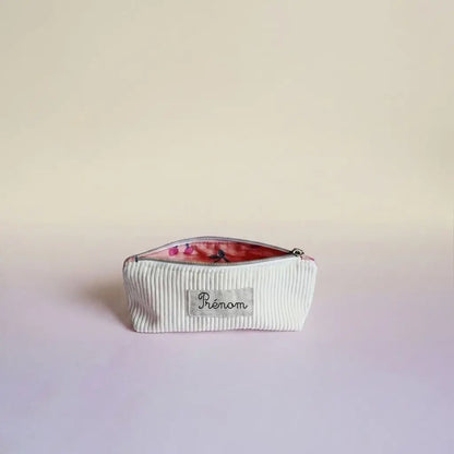 Trousse d'école blanc cassé en velours côtelé, doublure rose motif cerises entrouverte et étiquette prénom sur le devant