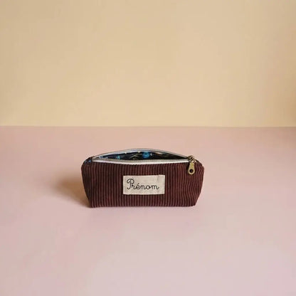 Trousse d'école prune en velours côtelé, doublure sombre à motif bleu et étiquette prénom au centre
