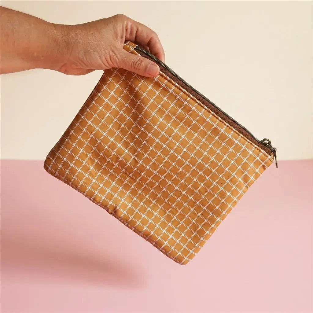 Pochette plate zippée en tissu à carreaux ocre et blanc, zip bronze, tenue en l’air