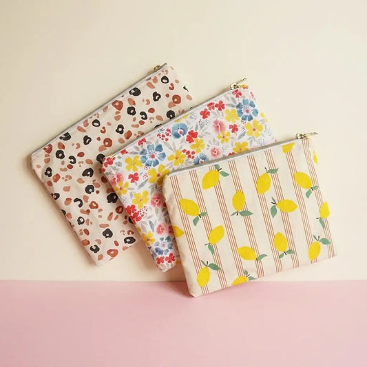 Trois trousses plates zippées à motifs léopard, fleurs et citrons présentées côte à côte