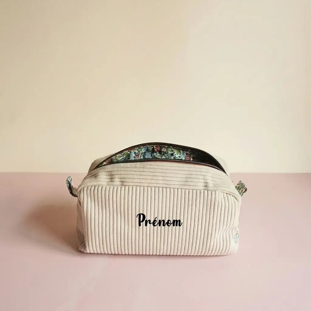 Trousse de toilette écru en velours côtelé, zip foncé ouvert sur une doublure fleurie, prénom devant