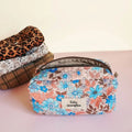 Trousse de toilette fleurie bleue et orange avec étiquette à personnaliser, autres modèles empilés