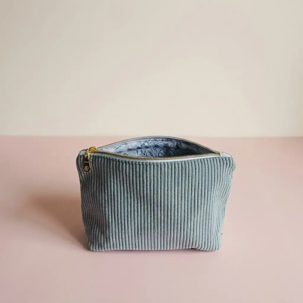 Trousse zippée en velours côtelé bleu clair entrouverte, doublure imprimée et fermeture dorée