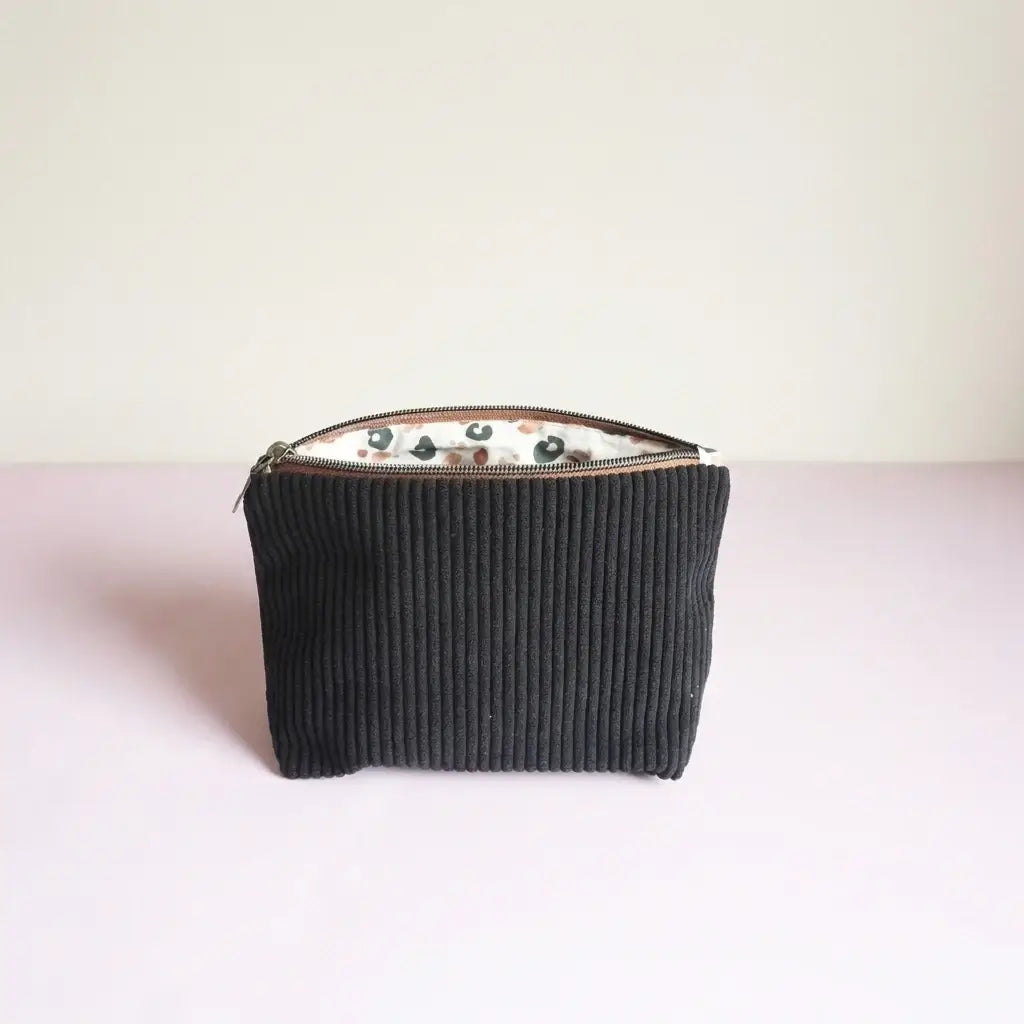 Trousse zippée noire en velours côtelé, doublure blanche à motif léopard, vue de face
