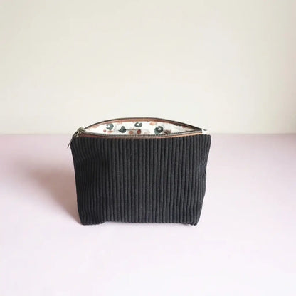 Trousse zippée noire en velours côtelé, doublure blanche à motif léopard, vue de face