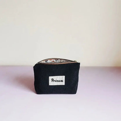 Trousse zippée noire en velours côtelé avec étiquette prénom blanche et zip bronze
