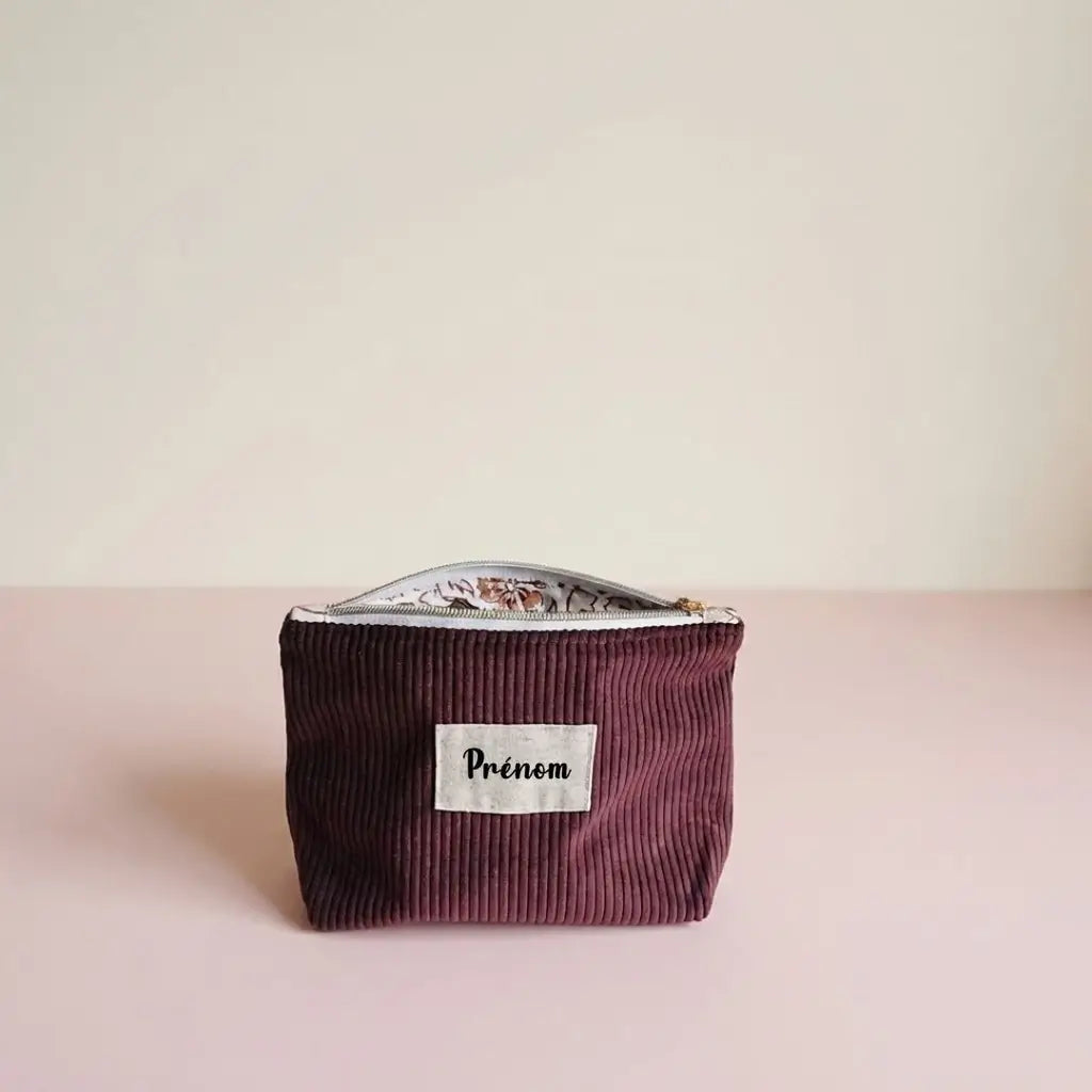 Trousse zippée prune en velours côtelé, étiquette prénom et doublure fleurie visible